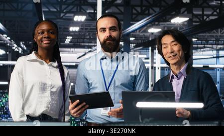 Happy data center colleagues collaborating on neural network software development. Cheerful teamworking server hub coworkers implementing machine learning technology in workplace, camera A Stock Photo