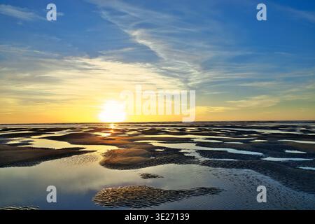Summer sun setting on the horizon over pool of water at low tide. Stock Photo