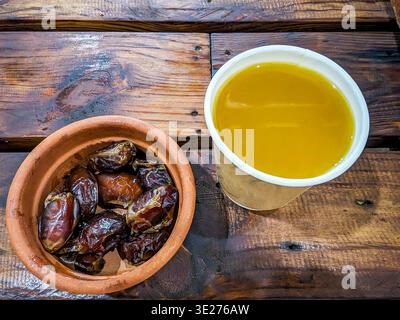 Top view of a plate of dates and Arabic coffee placed on the wooden table Stock Photo