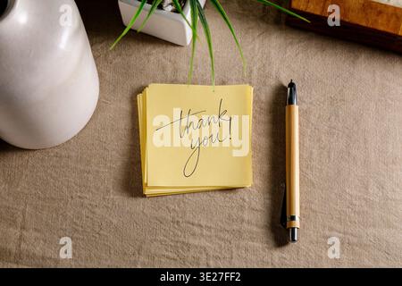 Thank you message on yellow sticky note with pen on desk, gratitude and appreciation concept. Stock Photo