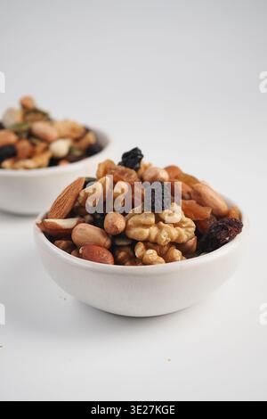 Nut and dried fruit mix in white bowls on a light surface Stock Photo