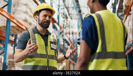 Talking, teamwork and men in warehouse for logistics, shipping and planning for delivery schedule. Supervisor, factory and workers in discussion for Stock Photo