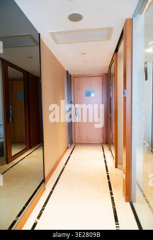 Modern hotel corridor with wooden doors and mirrored walls in Shanghai, China Stock Photo