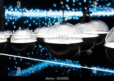 Modern spherical pendant lights hanging in futuristic exhibition space with blue bokeh background Stock Photo