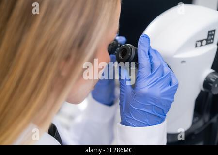A technician examines a sample using a high resolution digital microscope in a sterile laboratory setting. Stock Photo