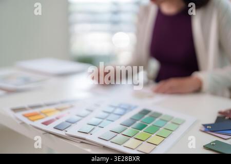Creative professional adult Asian woman selecting vibrant color swatches from palette Focus on design process for project branding Modern bright works Stock Photo