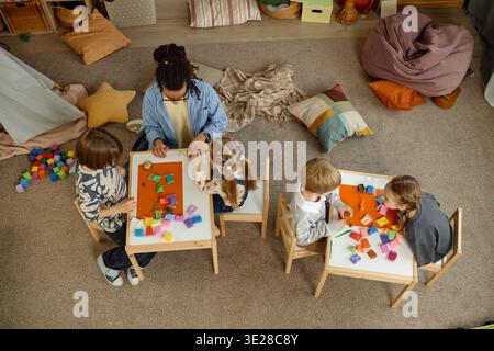 Multiethnic Group of Children and Male Teacher Engaging in Creative Play Stock Photo