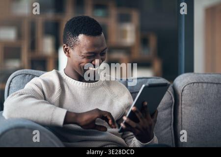 Relax, black man and laugh with tablet on sofa for comedy movie, funny online show and weekend break. Happy, person and digital app in home for Stock Photo