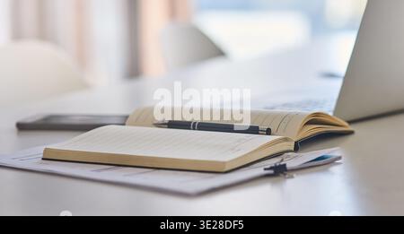 Empty, desk and documents with notebook in office for research notes, journalism schedule and to do list. Journal, laptop and paperwork at publishing Stock Photo