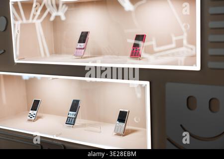 Vintage mobile phones displayed in illuminated glass cases at a retro tech store in Tokyo, Japan Stock Photo