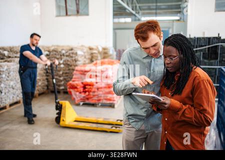 Diverse warehouse colleagues using digital tablet for inventory management Stock Photo