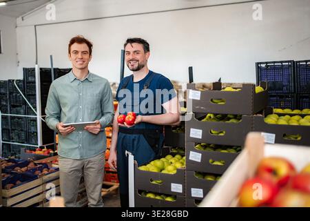 Produce workers discussing apples in fruit warehouse Stock Photo