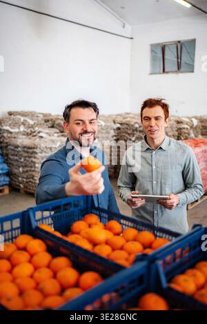Men inspecting oranges in warehouse for quality control Stock Photo