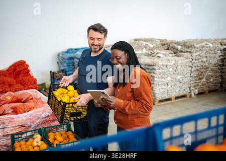 Farmers checking fresh citrus inventory in warehouse with tablet Stock Photo