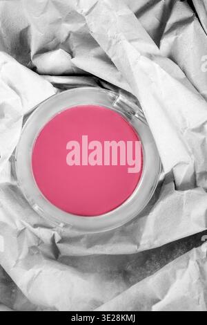 Pink matte blush round box lying in white crumpled packaging paper Stock Photo