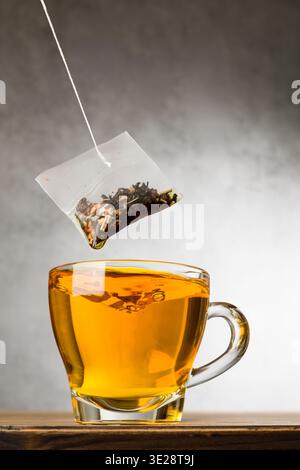 Glass cup of tea on wooden table with tea bag. Stock Photo