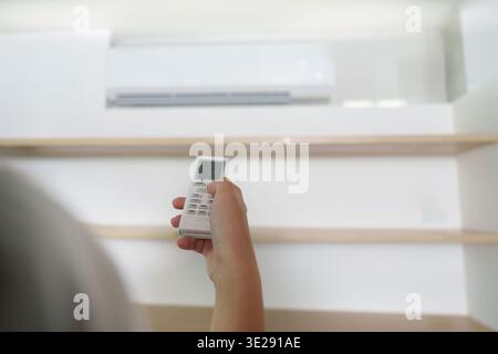 Air Conditioning Control. Hand using remote to adjust temperature settings. Stock Photo