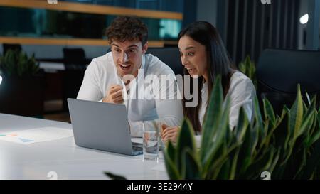 Happy two Caucasian workers business colleagues winning with laptop yelling celebrating win victory achieve businesspeople excited businessman with Stock Photo