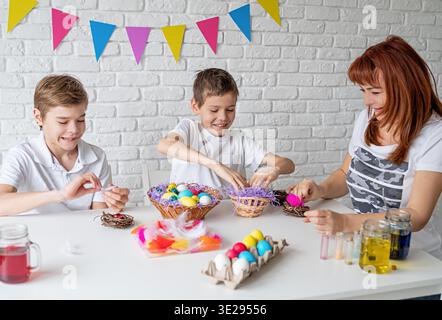 Easter holliday concept. Happy mother and two boys coloring Easter eggs. Selective focus || Model released Stock Photo