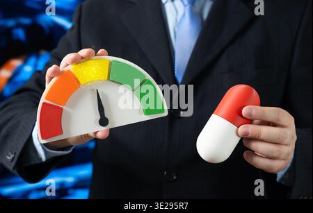 A medical capsule tablet and a rating scale showing an average yellow value. Average effectiveness with some side effects. Acceptable quality and balanced price in pharmaceutical evaluation Stock Photo
