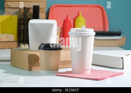 Eco friendly food packaging. Paper containers,cups, tableware and bag on white table against blue background, copy space Stock Photo