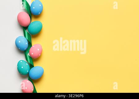 Easter colorful eggs are arranged in a row on a yellow and gray background. Greeting card with copy space. Stock Photo