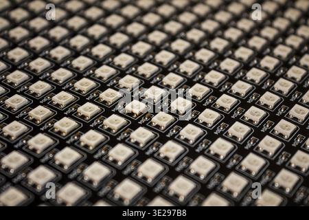 Close-up of an integrated LED panel with a dense grid of surface-mounted white light-emitting diodes on a black circuit board Stock Photo