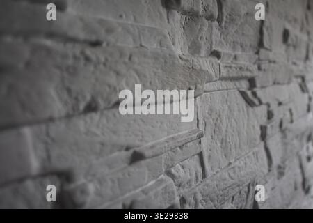 Close-up perspective of gray stacked stone cladding on an interior wall with deep shadows and rough texture Stock Photo