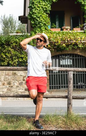 Man leaning on wooden fence in rural village Stock Photo