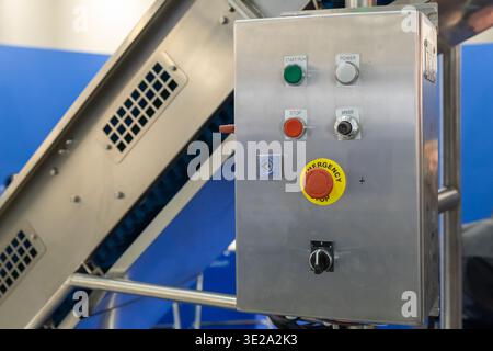 A stainless steel industrial control panel, featuring start, stop, power, and emergency stop buttons, along with a speed dial and key switch, is displ Stock Photo