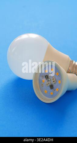 Different types of light bulbs placed on a bright blue surface in a well-lit space Stock Photo