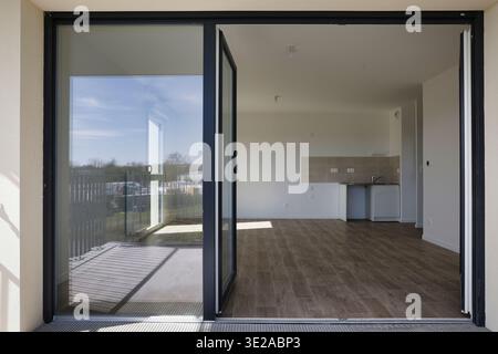 Tour of a new apartment in a residential building: an empty room. Empty living room, view of the kitchen area and an open bay window Stock Photo