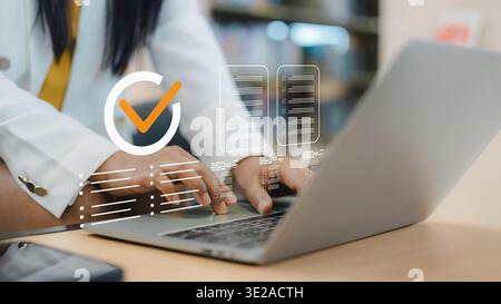 Businesswoman working on laptop with virtual checklist and orange checkmark icon. Concept of quality assurance, standard compliance, certified documen Stock Photo