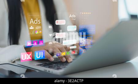 Businesswoman working on laptop for digital marketing and UX UI design. Virtual screen showing advertising chat, social media ads metrics, and user in Stock Photo