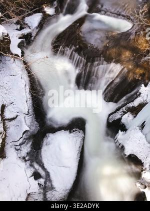 Kegon Falls in winter, Nikko National Park, Tochigi Prefecture, Japan, with snow and ice-covered rocks and flowing water Stock Photo