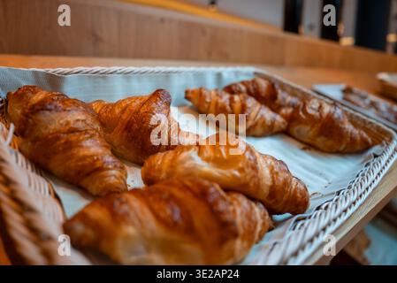 Wicker tray of glossy croissants on wooden counter in Zermatt, Switzerland Stock Photo