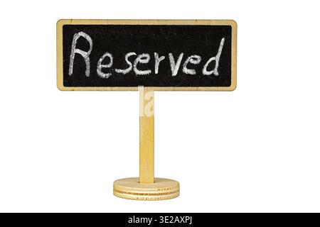 A charming handwritten chalk Reserved sign displayed on a small blackboard tablet mounted on a wooden pole stand, isolated cleanly on white background Stock Photo