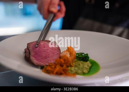 Chef arranges medium rare beef with tweezers in Oberlech, Austria Stock Photo