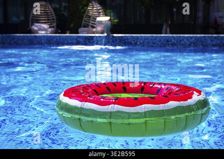 Colorful watermelon float in a bright blue swimming pool on a sunny day in summer Stock Photo