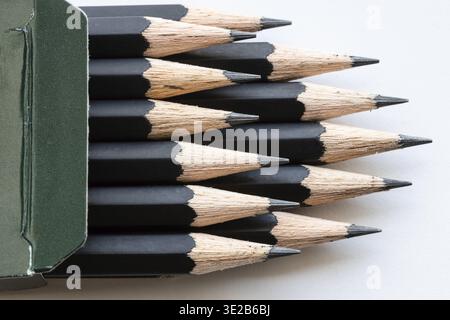Sharp tips of set of black graphite pencils close up in green cartboard box on white background Stock Photo