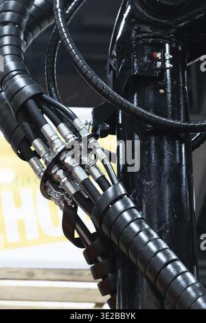 Berlin, Germany - January 22, 2024: Hydraulic hoses and connectors are visible on industrial machinery with a black finish and detailed textures Stock Photo