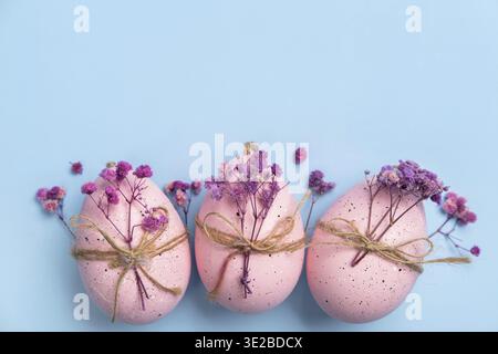Happy Easter day! ?omposition with modern Easter eggs and spring flowers on blue background. Easter holiday background with stylish eggs decorations. Stock Photo