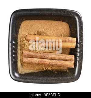 Top view of cinnamon sticks and powder in black bowl isolated on white background Stock Photo