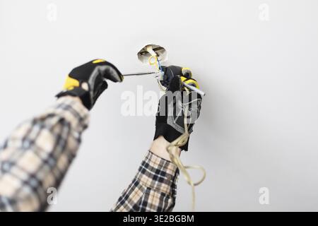 Electrician repairing electrical wiring of ceiling lamp at home Stock Photo