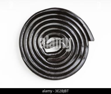 Top view of spiral from black liquorice candy on white plate Stock Photo