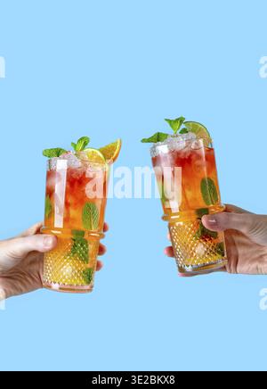 Strawberry mojito. Female hands holding two glasses with summer cocktails with ice and mint Stock Photo