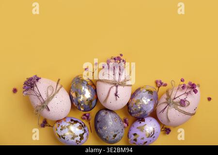 Happy Easter day! ?omposition with modern Easter eggs with gold decorations and spring flowers on yellow background. Easter holiday background with st Stock Photo