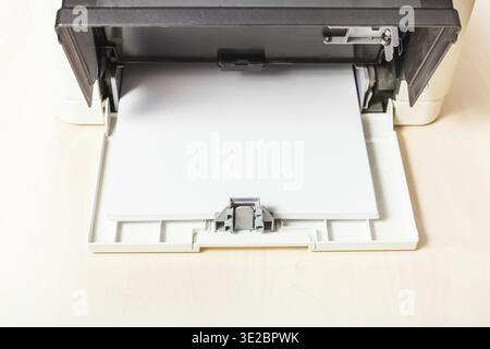 Sheets of blank white paper in printer tray of multi function device on table in office Stock Photo