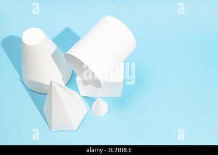 Above view of various hand-crafted paper geometric shapes on turquoise blue background with copyspace Stock Photo