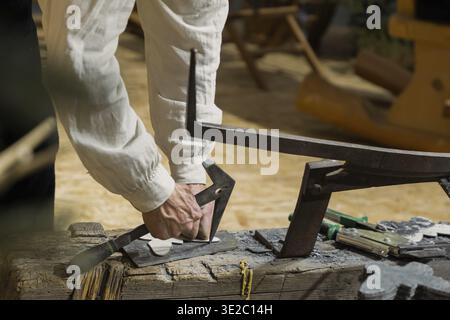 Berlin, Germany - January 22, 2024: Craftsman is using various tools on a wooden workbench in a rustic workshop environment Stock Photo